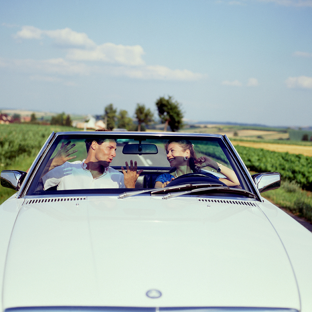 COUPLE IN CONVERTIBLE CAR AND WOMAN DRIVING