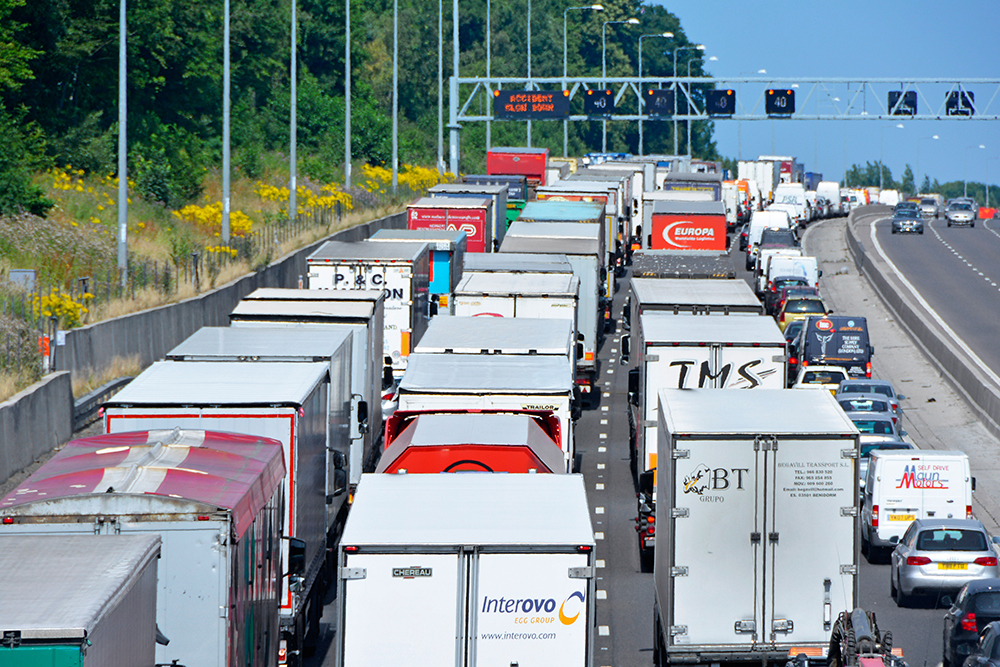 Four lane M25 motorway and gridlocked (mainly) trucks with articulated trailers stuck in queue because of an accident