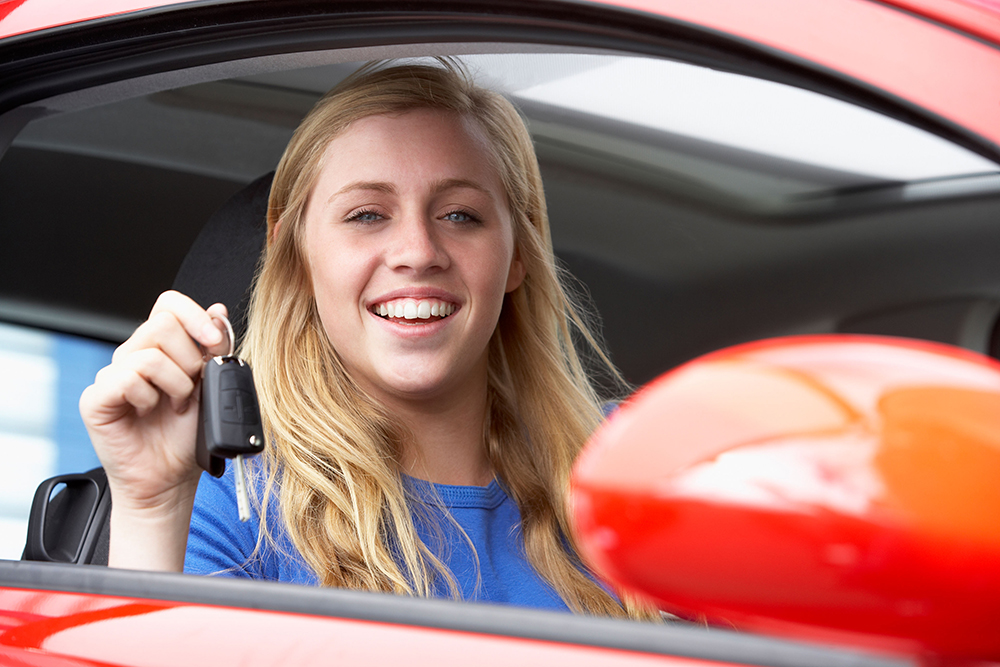Teenage Girl Sitting In Car, Holding Car Keys And Smiling At The Camera