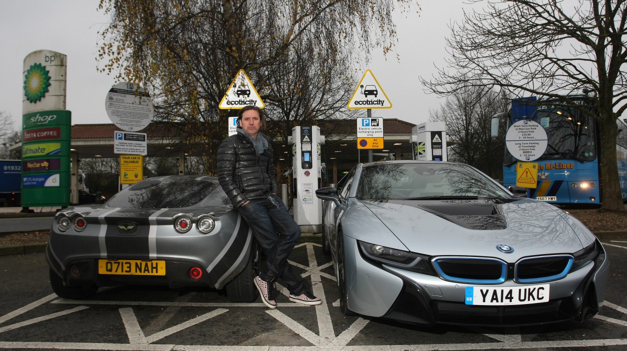 Dale Vince of Ecotricity poses next to his electric car rapid charging point at a motorway service station