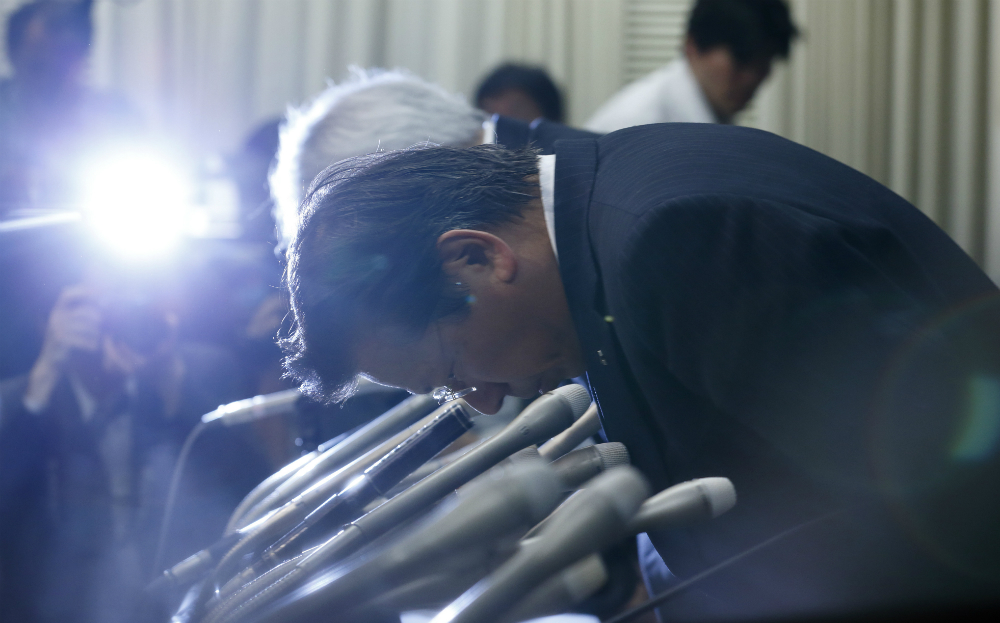 Mitsubishi Motors president Tetsuro Aikawa bows at fuel economy press conference