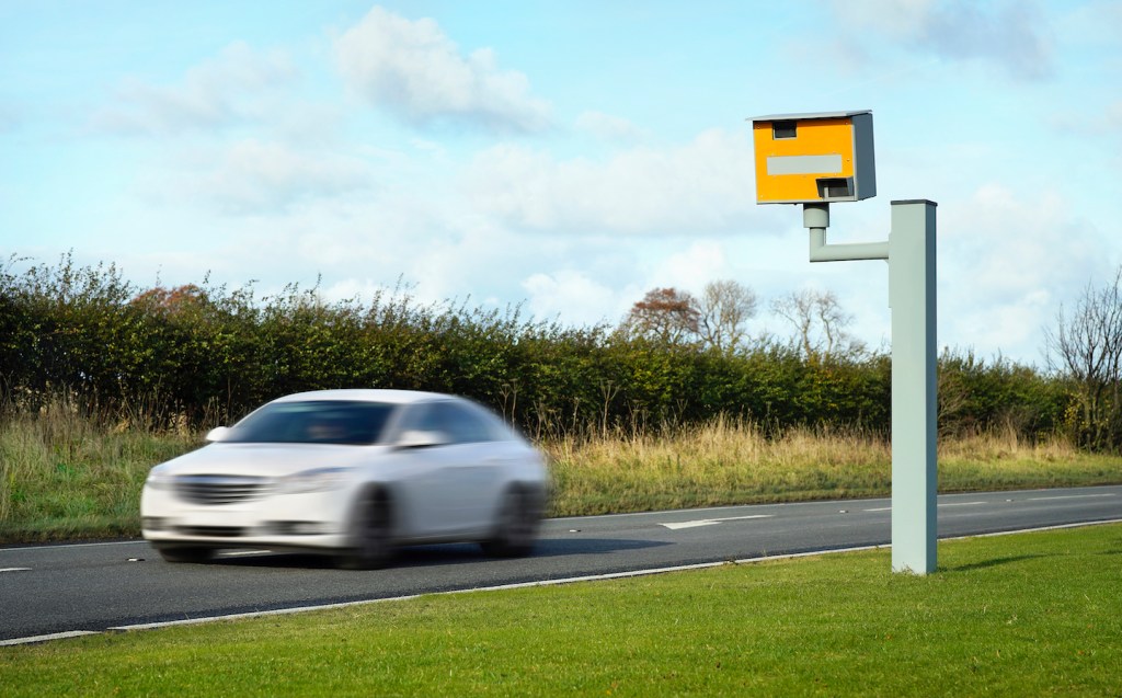 A car passes a speed camera on a rural road