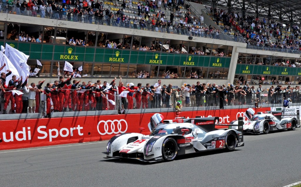 Audi celebrates the win of the Audi R18 E-Tron Quattro Hybrid N°2 driven by French Benoit Treluyer (L) and the Audi R18 E-Tron Quattro Hybrid N°1 driven by Danish Tom Kristensen at the end of the the 82nd 24 Hours of Le Mans endurance race on June 15, 2014