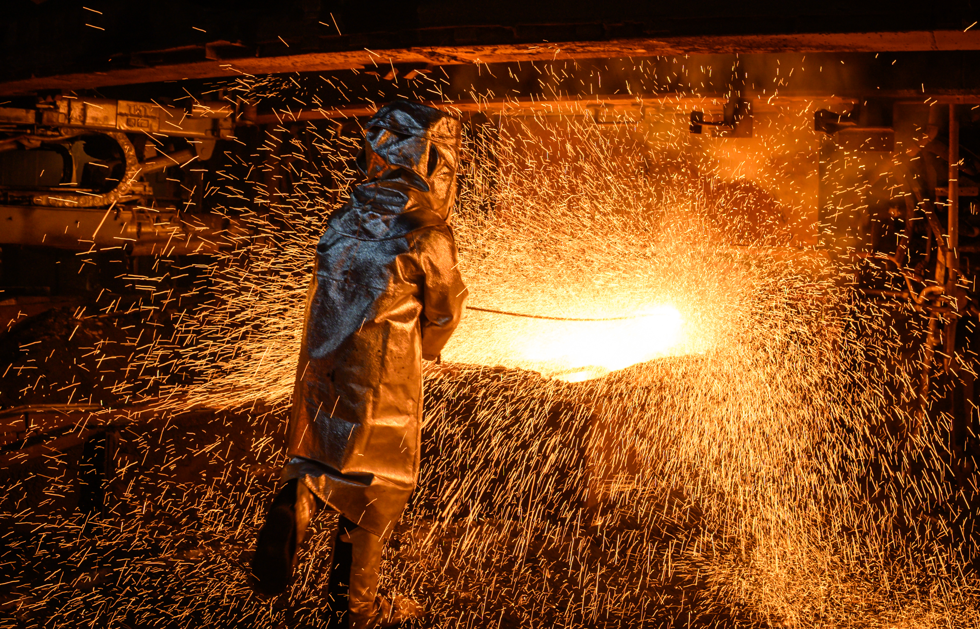 A worker in a fire suit seen supervising the flow of hot liquid metal as it flows from a furnace at the plant. Production of matte nickel at the PT Vale nickel plant, in Sorowako, South sulawesi, Indonesia, the plant is targeting a production of 75,000 metric tons in 2019. (Photo by Hariandi Hafid/SOPA Images/LightRocket via Getty Images)