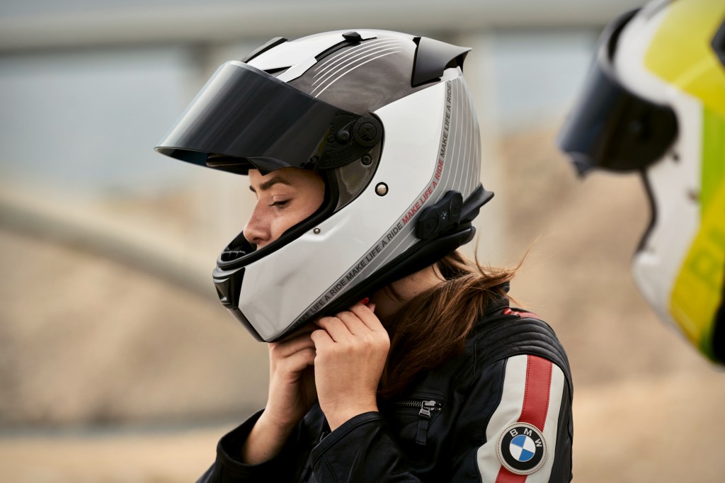 A woman does up her motorcycle helmet