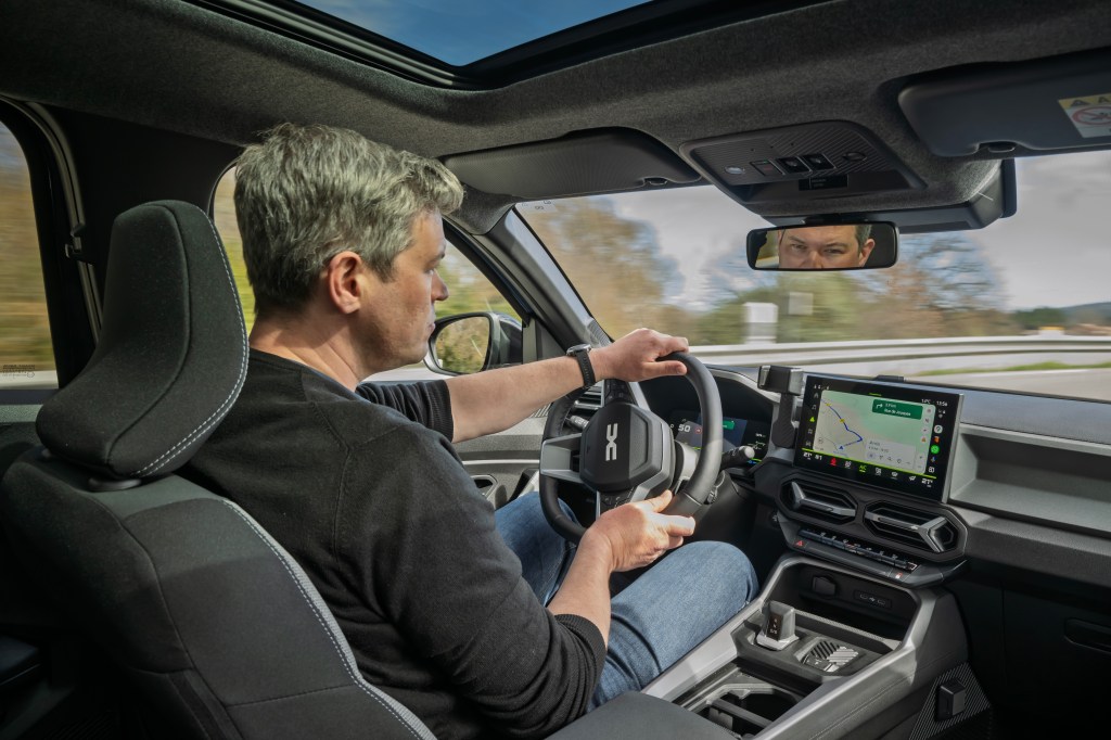 Will Dron Driving the 2025 Dacia Bigster, interior over-the-shoulder view